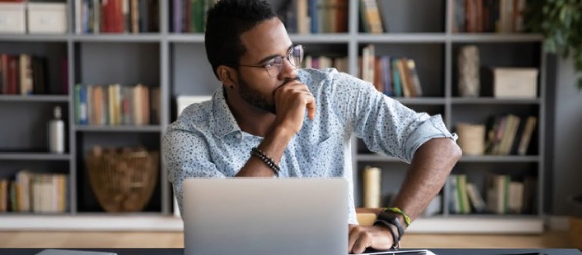 african-businessman-sitting-at-workplace-thinking-over-problem-picture-id1253877157
